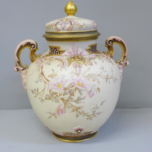 606 - A Royal Worcester scroll handled vase and cover, decorated and gilt with blossom on a shaded ivory g... 