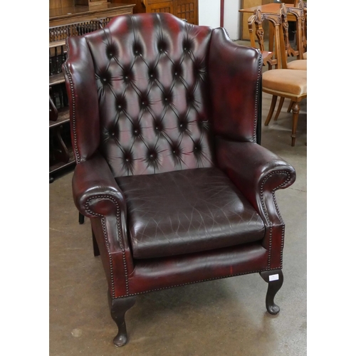 75 - An oxblood red leather Chesterfield wingback armchair