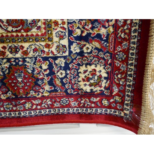 1325 - A red ground full pile Cashmere rug with floral medallion design, 170 x 120cm