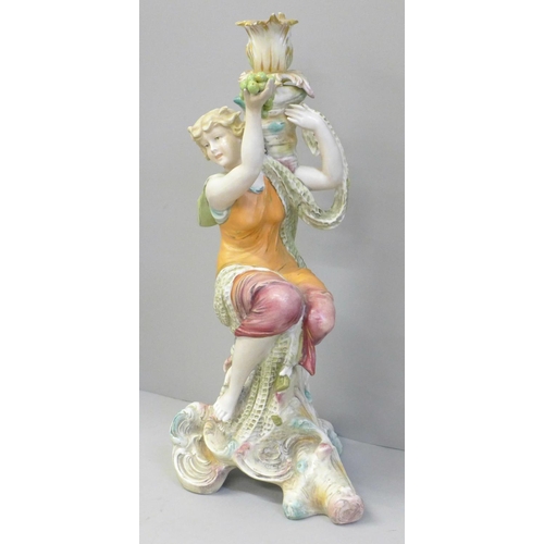 607 - A continental porcelain figural candlestick modelled as a girl seated on a tree stump holding up a b... 