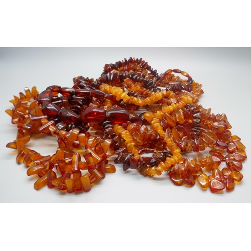 864 - A collection of nine amber necklaces and a pendant