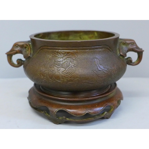 623 - A 19th Century bronze censer on a wooden base, cast mark to base, 18cm wide including elephant handl... 