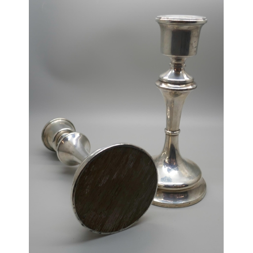 832 - A pair of silver candlestick holders with weighted bases, 18cm