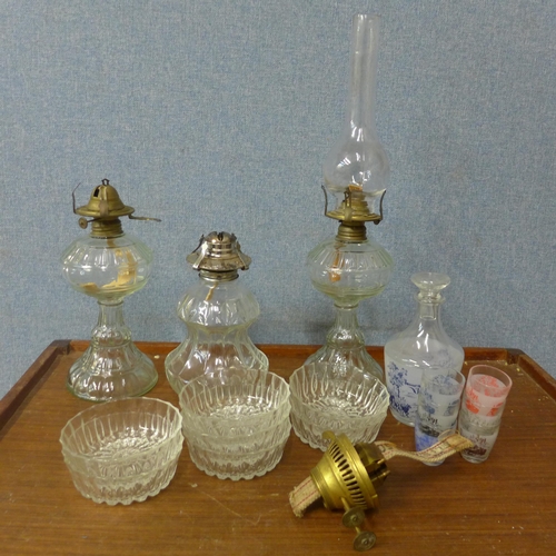 339 - Three glass oil lamps, a set of glass dishes, a decanter and shot glass set