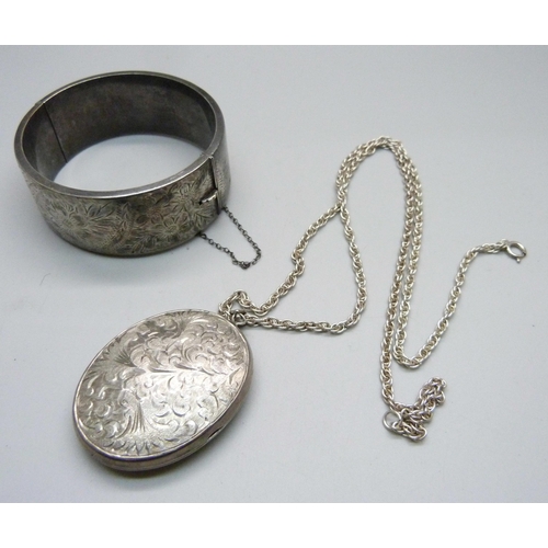 1015 - A large silver locket on a silver chain and a silver bangle, 74g