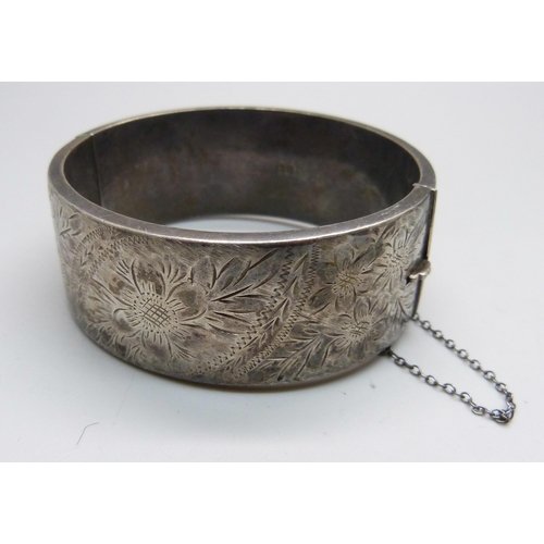 1015 - A large silver locket on a silver chain and a silver bangle, 74g