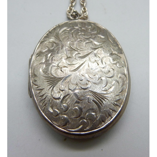 1015 - A large silver locket on a silver chain and a silver bangle, 74g