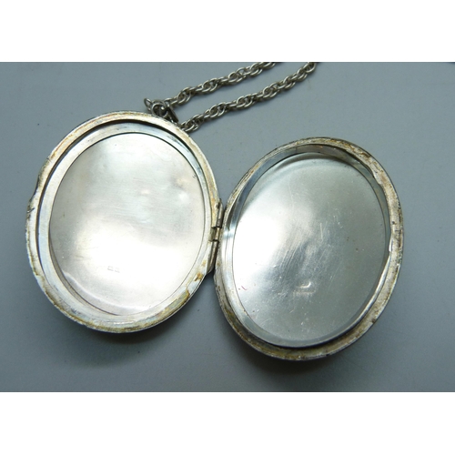 1015 - A large silver locket on a silver chain and a silver bangle, 74g