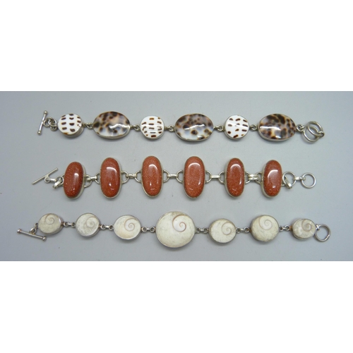 1025 - Three white metal bracelets; two set with shells one set with gold-stone