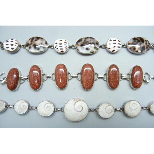 1025 - Three white metal bracelets; two set with shells one set with gold-stone