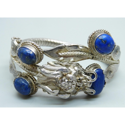 1049 - A white metal, lapis lazuli bangle with dragon detail