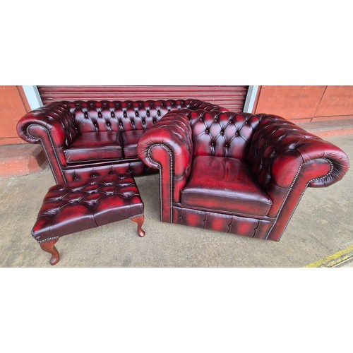 100B - An oxblood red leather Chesterfield three piece lounge suite, comprising, settee, club chair and sto... 