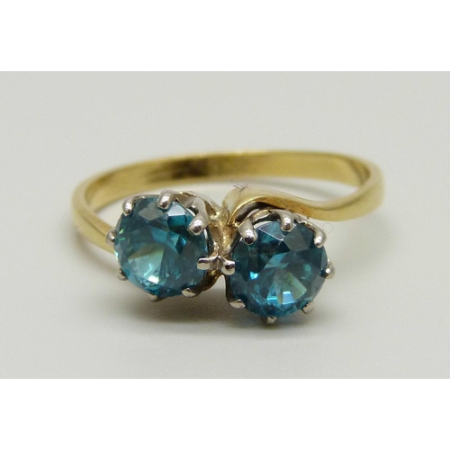 970 - An 18ct gold ring set with two blue zircon stones in a crossover design, 3.5g, Q