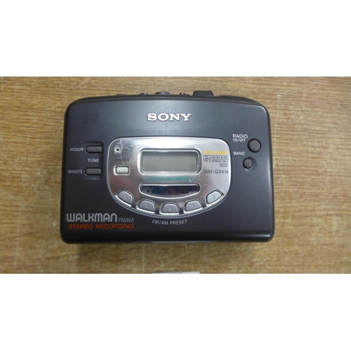 2123 - A Sony Walkman FM/AM stereo recording tape player and a pair of wired Apple earphones with lightning... 