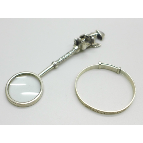 1002 - A child's silver bangle and a novelty magnifying glass pendant