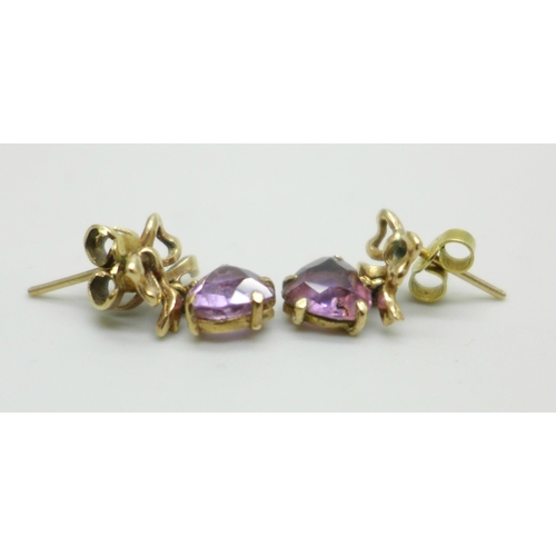 1012 - A pair of yellow metal earrings with bow detail, set with amethyst heart shape stones, 2.1g