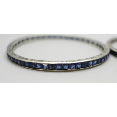 1038 - Two white metal bangles set with blue glass stones