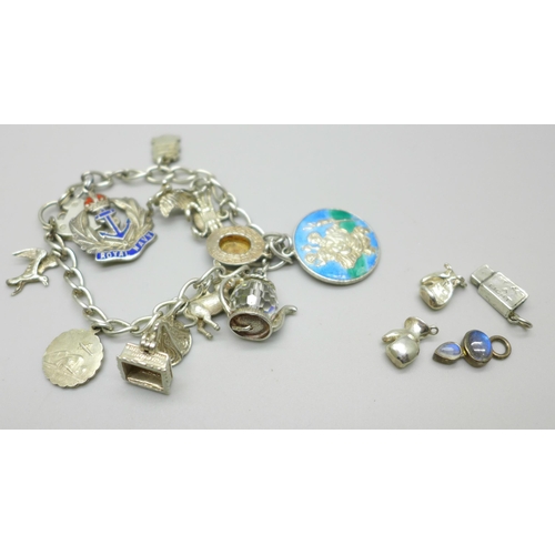 1066 - A silver charm bracelet with silver and white metal charms, 50g