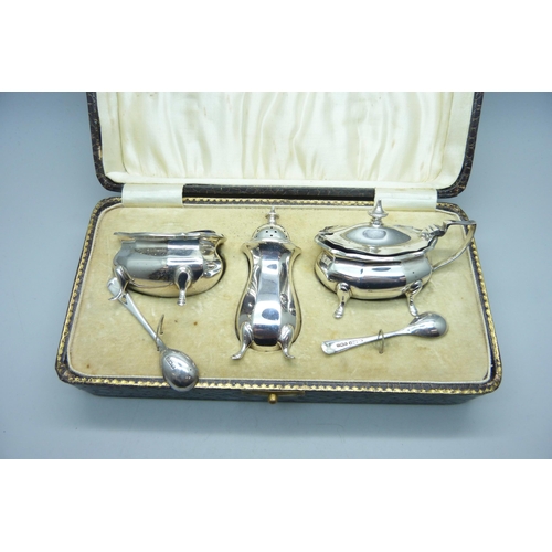 774 - A cased silver cruet set and two silver spoons, Birmingham 1925, 140g, one liner chipped