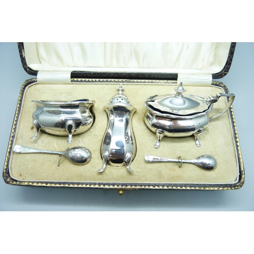 774 - A cased silver cruet set and two silver spoons, Birmingham 1925, 140g, one liner chipped