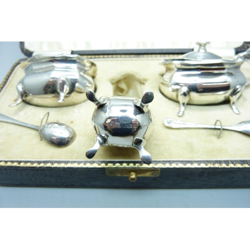 774 - A cased silver cruet set and two silver spoons, Birmingham 1925, 140g, one liner chipped