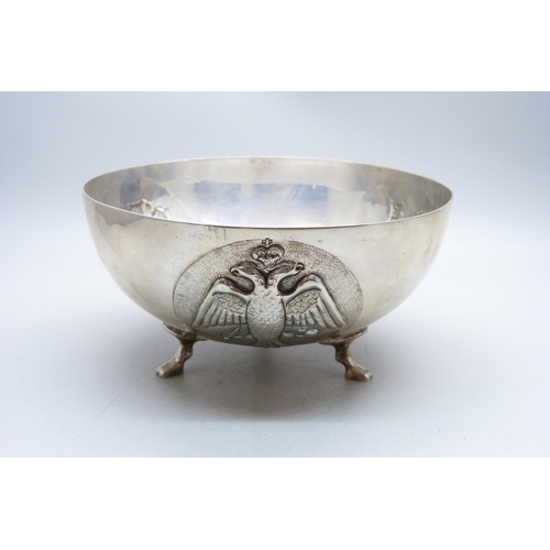 782 - An 830 silver bowl on three feet and with three circular panels with double headed eagle, Corinthian... 