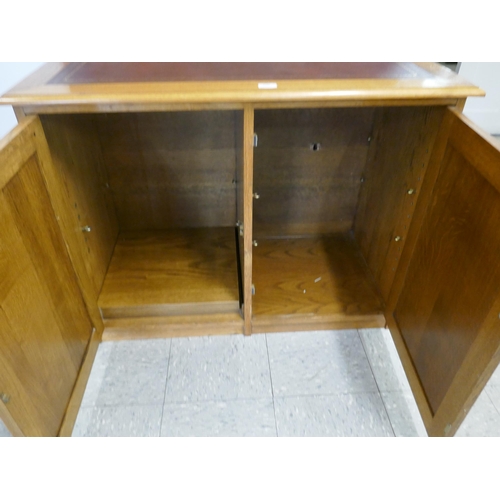 1543 - An oak leather topped two door cabinet