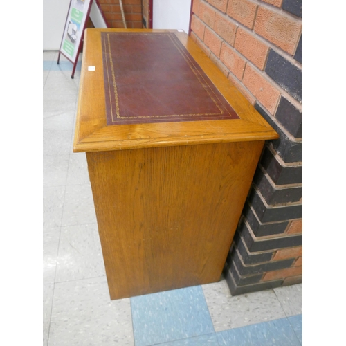 1543 - An oak leather topped two door cabinet