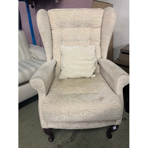 1544 - A cream fabric three piece suite comprising of a three seater sofa, two armchairs and a wingback cha... 