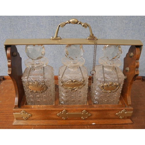 356 - An oak tantalus, with three glass decanters and plated spirit labels