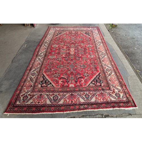 216C - An eastern hand knotted red ground rug, 333 x 229cms