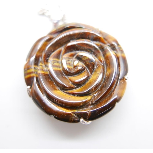 1068 - A carved silver mounted tigers eye pendant on a silver chain and a pair of tigers eye earrings, chai... 