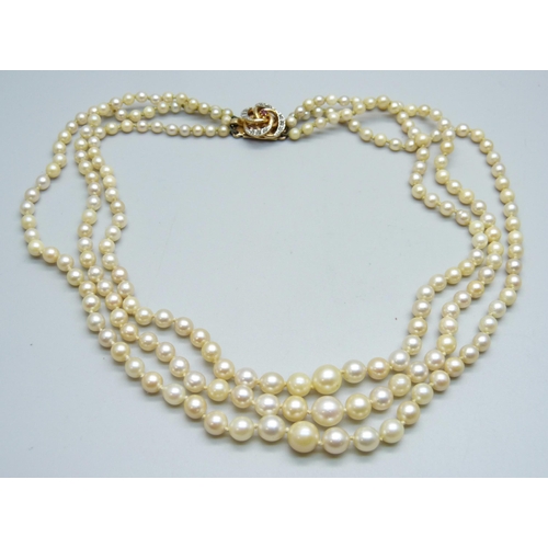 1013 - A three strand pearl necklace with a ruby and diamond clasp