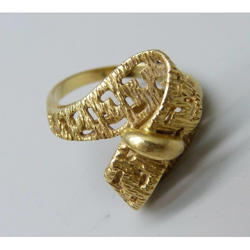 1041 - A yellow metal ring, (tests as 18ct gold, hallmark worn), with stylised cross over ribbon of gold wi... 