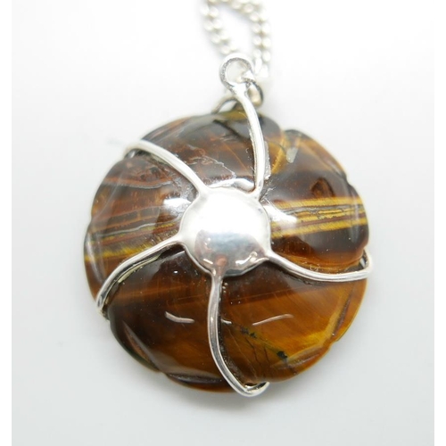 1068 - A carved silver mounted tigers eye pendant on a silver chain and a pair of tigers eye earrings, chai... 