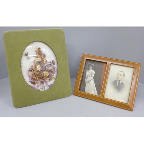 666 - An Edwardian dried flower display under a convex glass with silk photograph frame and a double leath... 