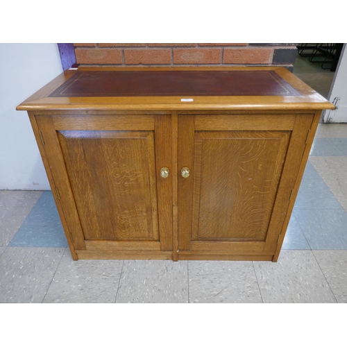 1596 - An oak leather topped two door cabinet