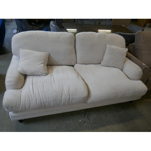 1544 - A cream upholstered three seater sofa - damaged leg - stained