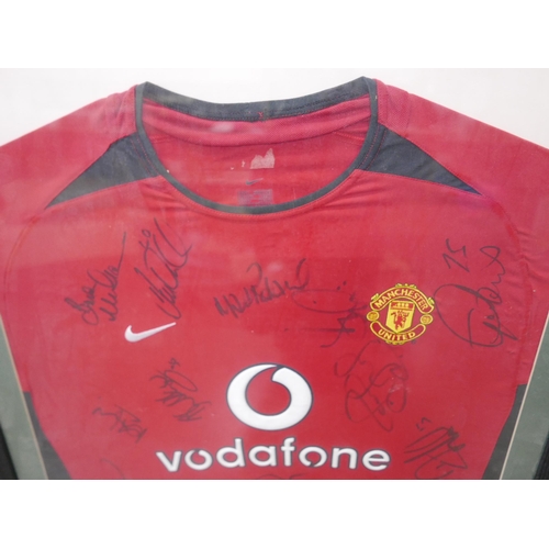 606 - A framed Manchester United football shirt with the team's autographs