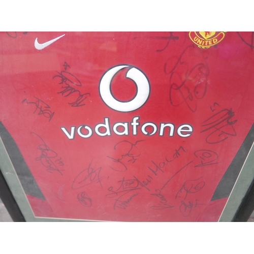 606 - A framed Manchester United football shirt with the team's autographs