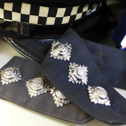 699 - A collection of Police memorabilia; helmets, caps, lapel badges, shoulder flashes, etc.