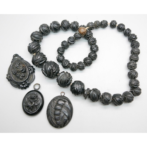 961 - Two jet pendants, one other pendant and a carved jet bead necklace, (some beads a/f)