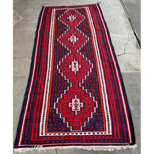 154B - A large red and navy blue ground rug 314 x 144cms