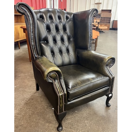74 - A green leather Chesterfield wingback armchair