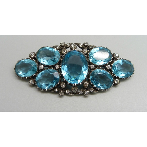 1127 - A white metal early 20th Century brooch with paste stones, tests as silver, 64mm