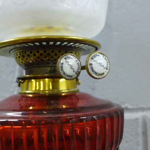 789 - An Art Nouveau brass oil lamp with ruby glass reservoir