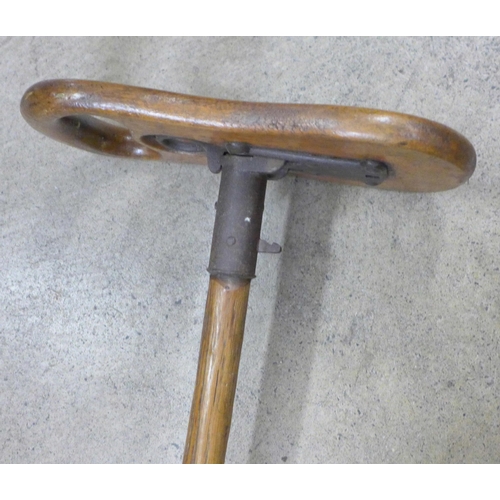 800 - An early 20th Century wooden shooting stick with carved shooting emblem in the seat