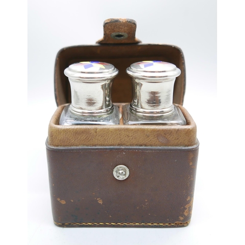 871 - A pair of perfume bottles with enamelled tops in a leather travel case