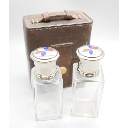 871 - A pair of perfume bottles with enamelled tops in a leather travel case