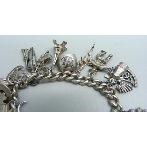 974 - A sterling silver charm bracelet with twenty charms, 66.8g